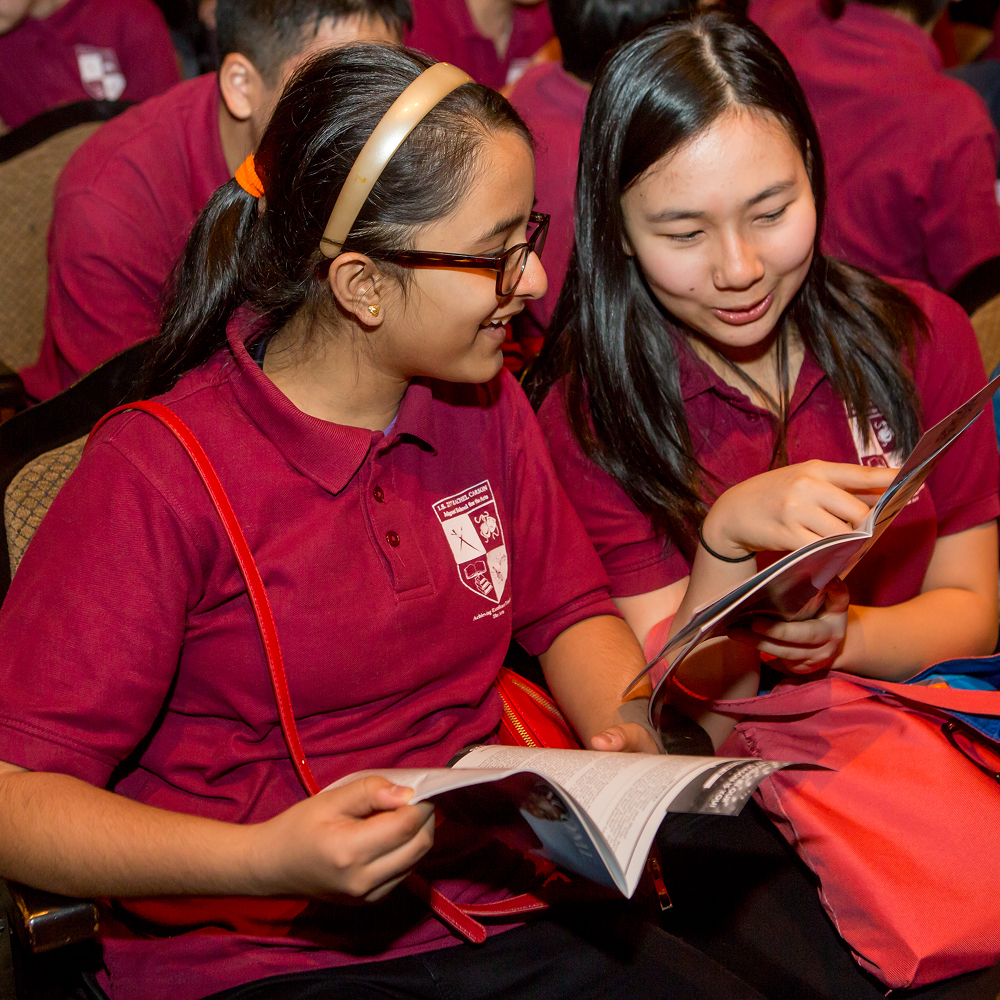Students sit together in theater seats reading a show program during a Roundabout Theatre Company education event.